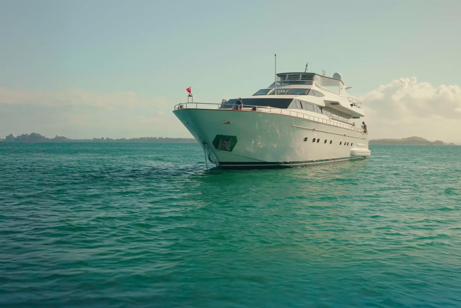 A luxury yacht at anchor with the Auckland skyline at dusk